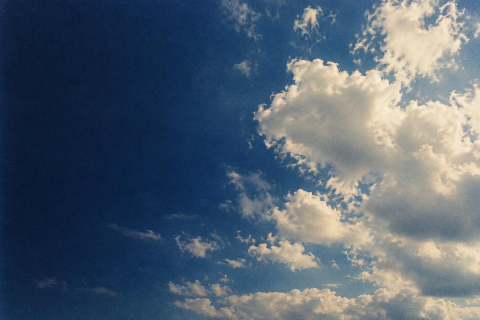 A deep blue sky with sunlit white clouds gathering on the right.